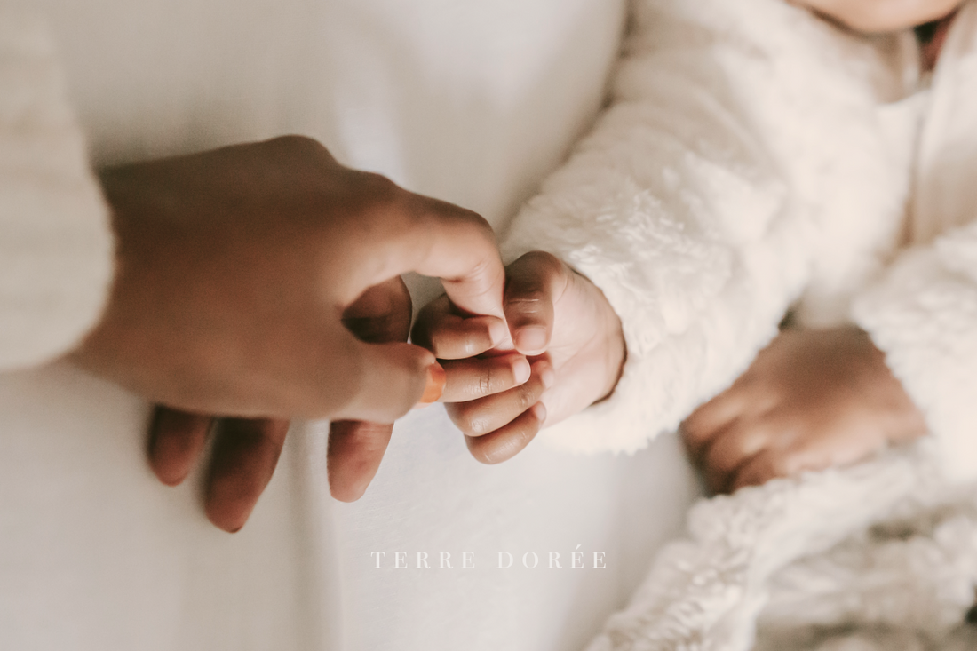 Banner image featuring a woman holding a newborn baby's hand in bed with a light background.
